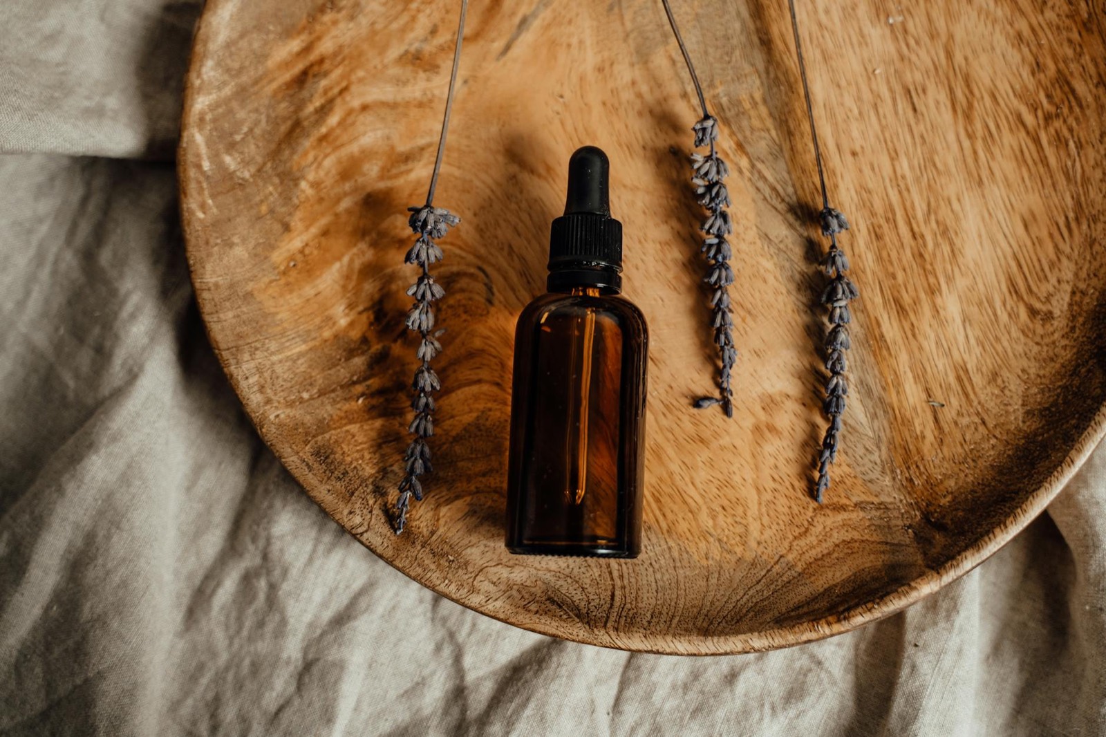 An amber dropper bottle of natural oil with dried lavender